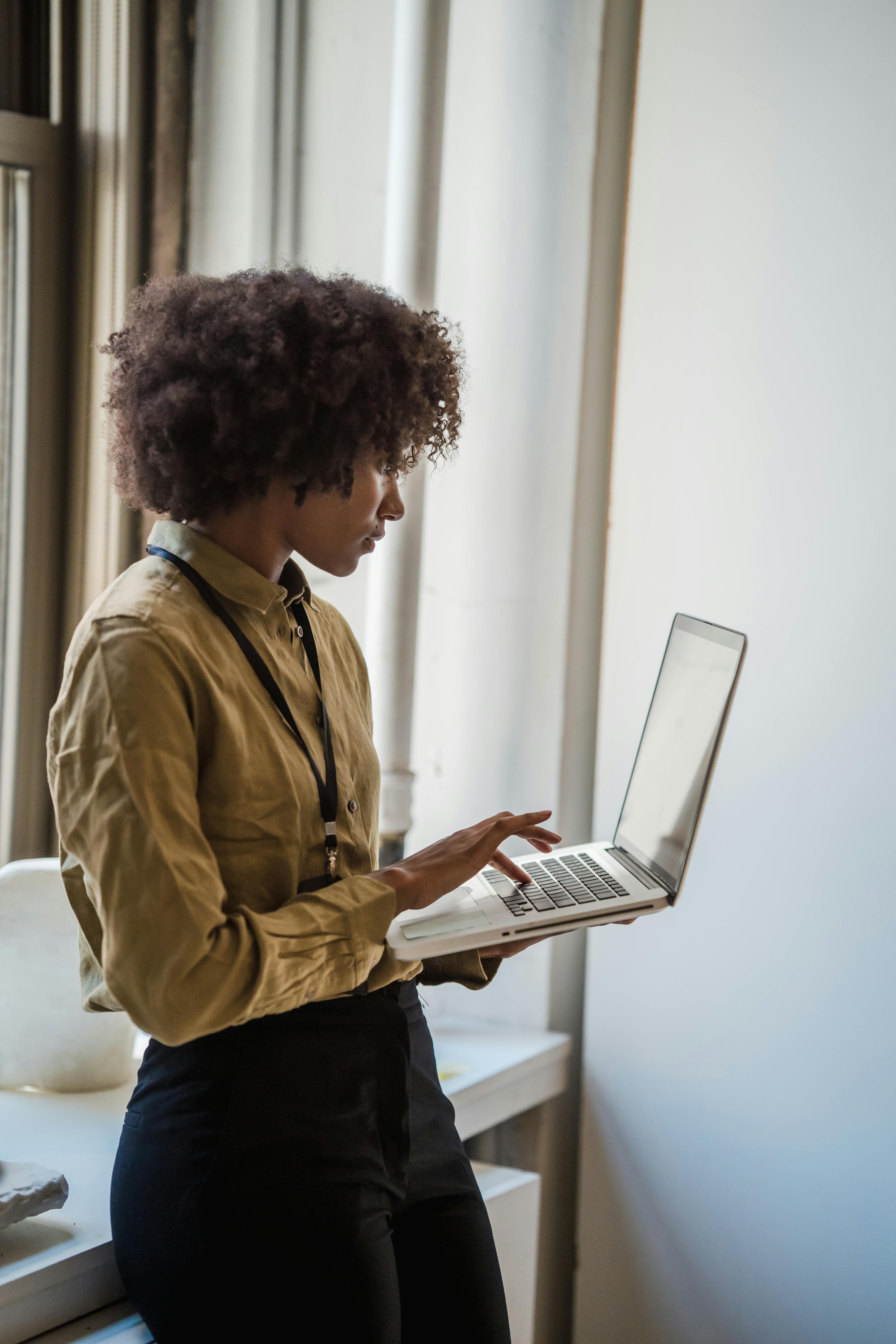 Side profile of a businesswoman using a laptop in a well-lit office environment.